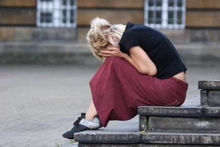 A person sitting on steps with her face in her hands AI-generated content may be incorrect.