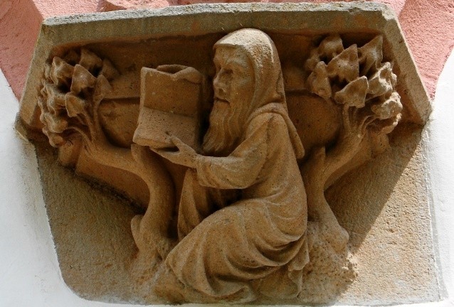 A stone carving of a person holding a book AI-generated content may be incorrect.