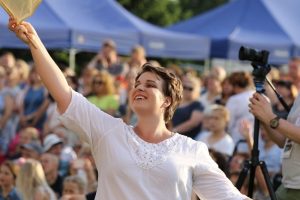 A person holding her hands up and smiling Description automatically generated
